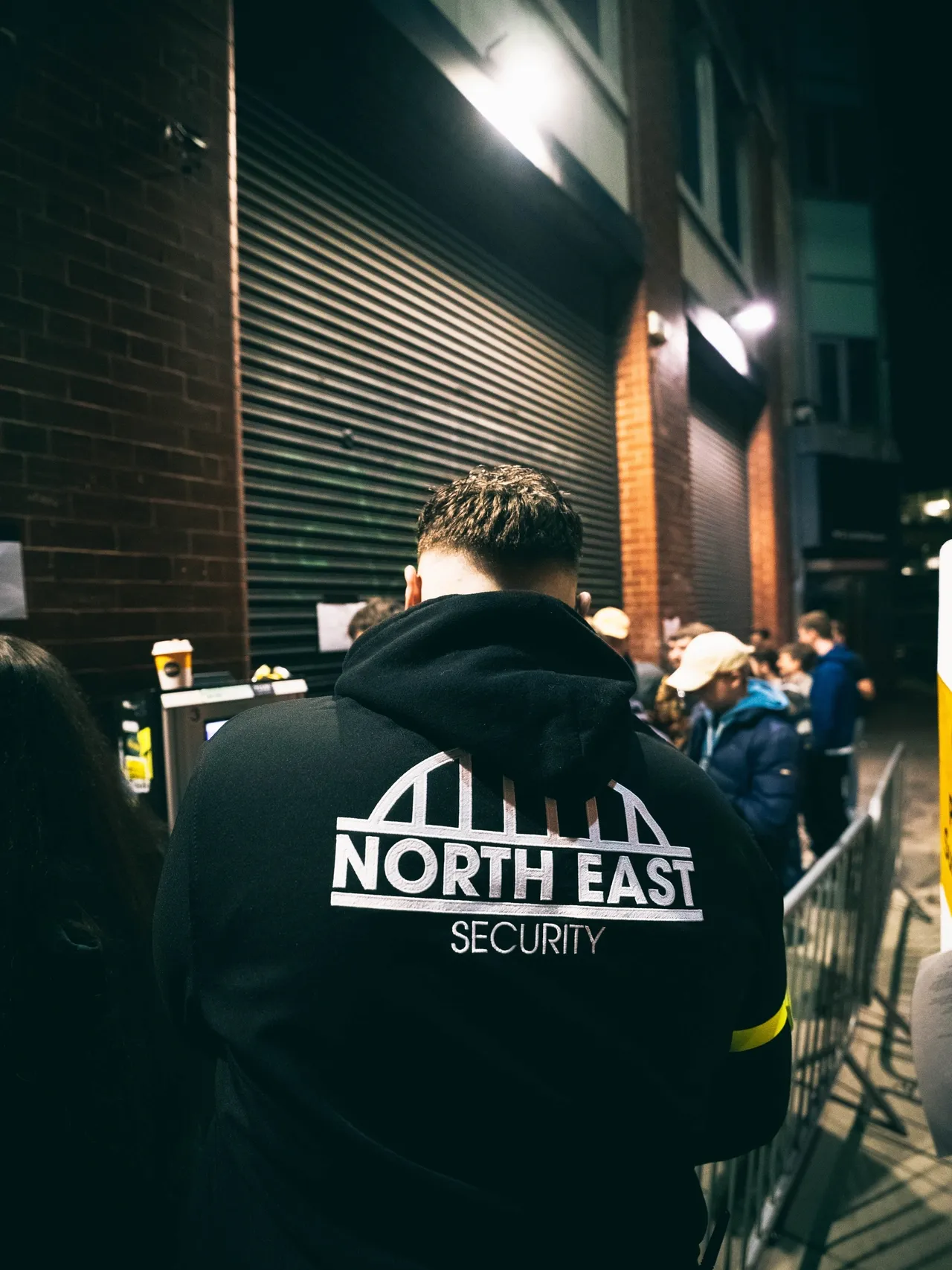 North East Security officer in branded hoodie managing an event queue at night